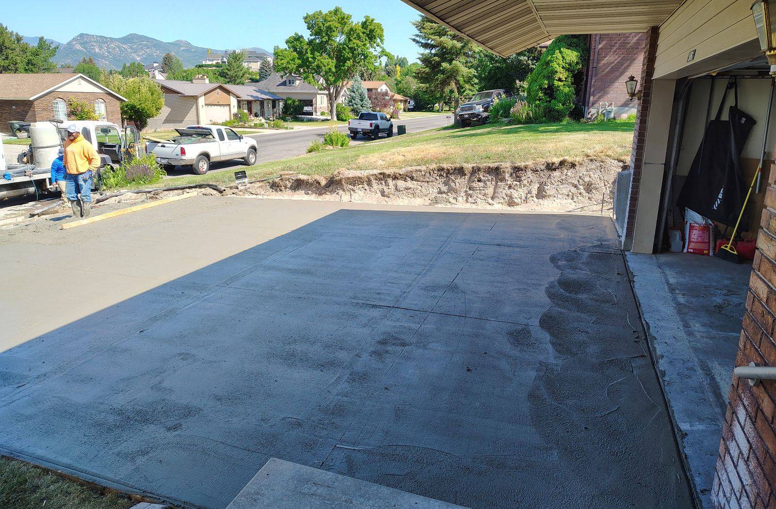 Freshly poured concrete driveway curing under a carport